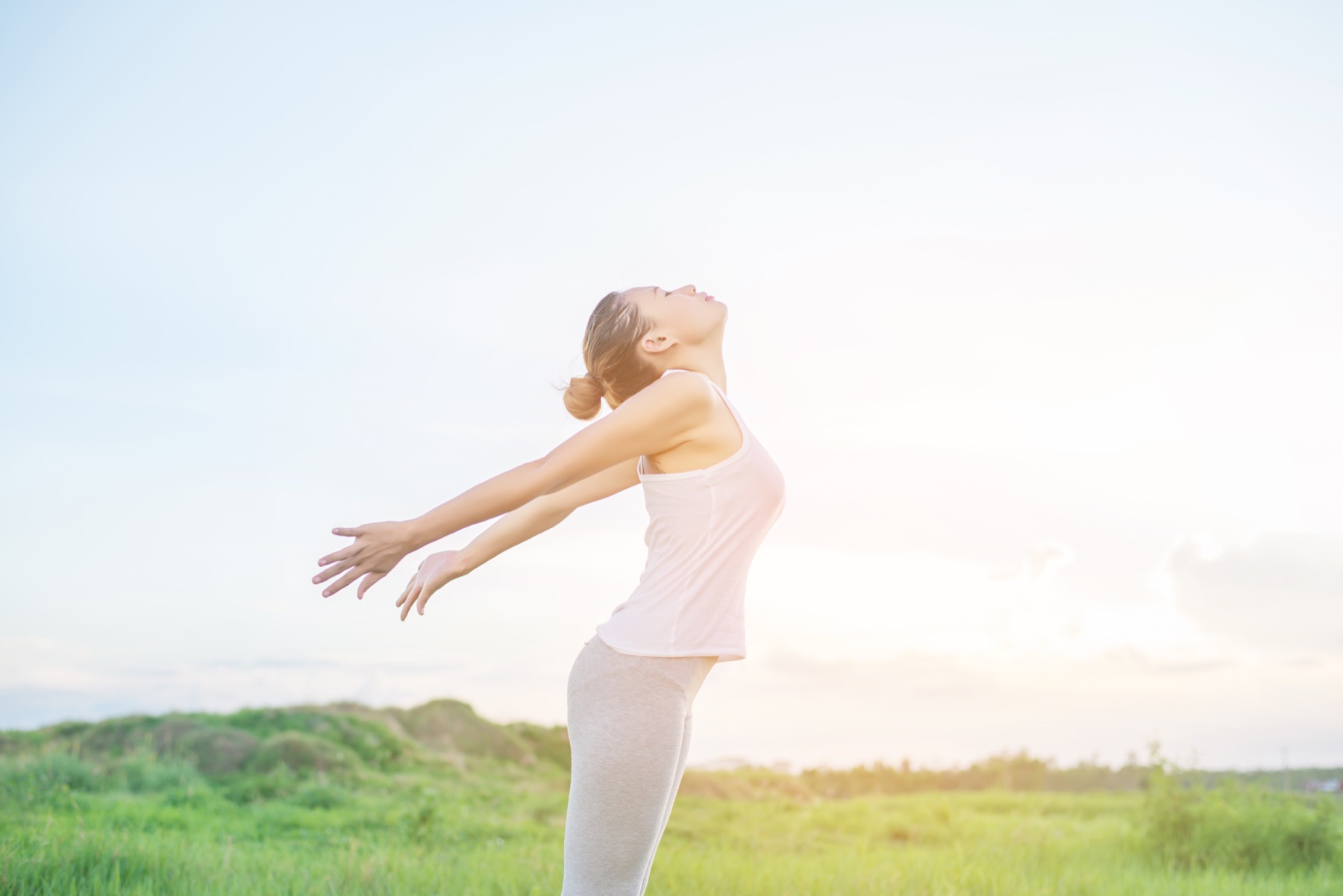 Woman breathing deeply outdoors in a green field
